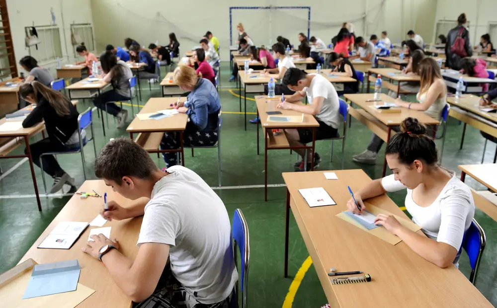 Candidati alla prova scritta del concorso Allievi Finanzieri vigilati da un ufficiale della Finanza in divisa militare.