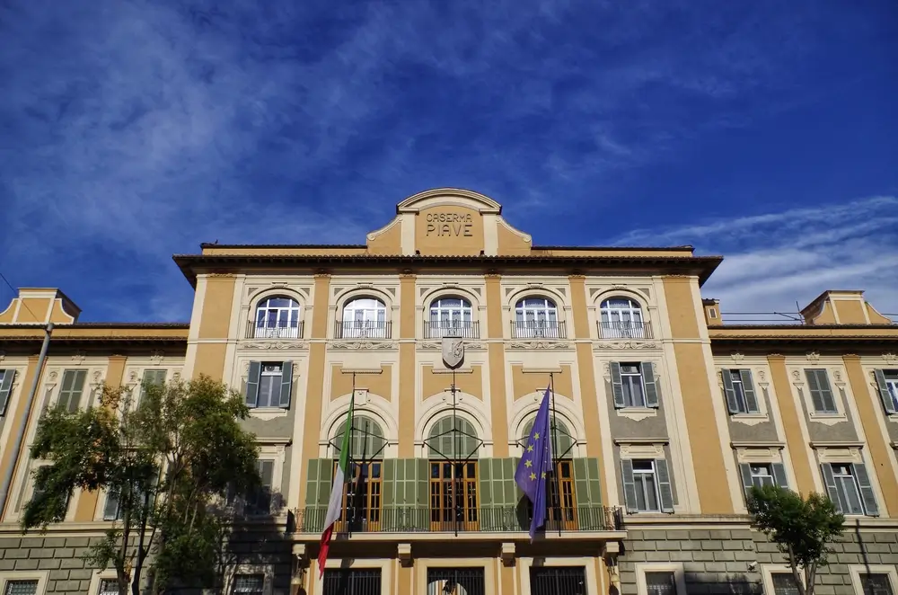 Facciata della Caserma Piave, sede della scuola della Guardia di Finanza con bandiere italiana ed europea.
