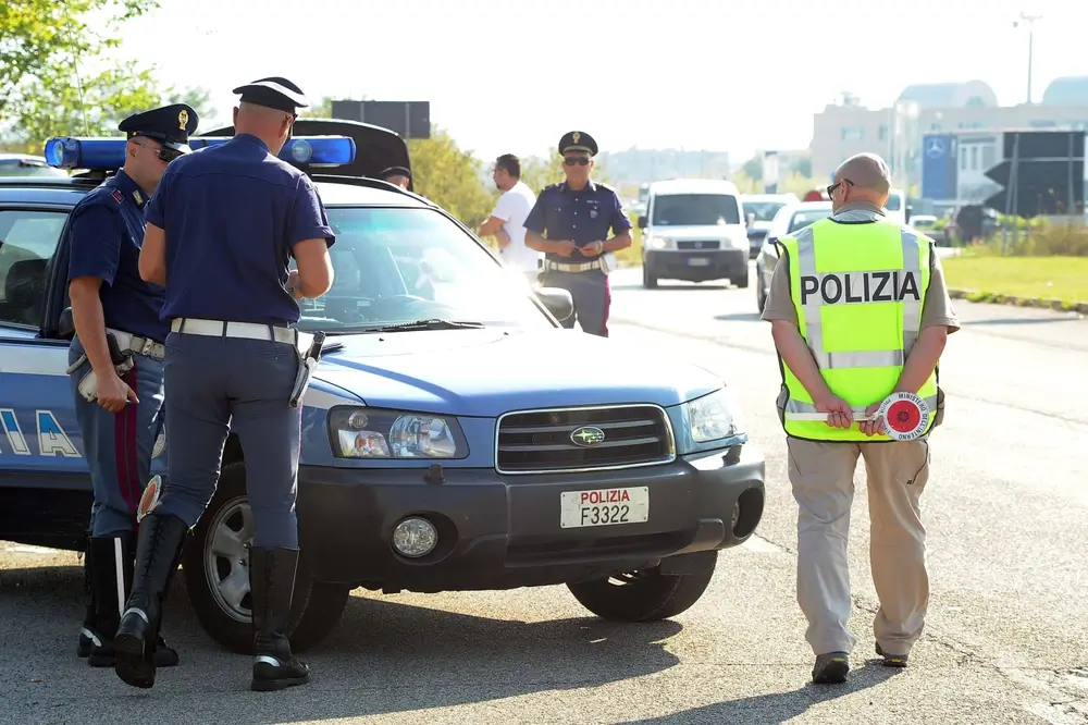 Agenti della Polizia di Stato effettuano un controllo stradale con pattuglia e paletta segnaletica lungo la carreggiata.