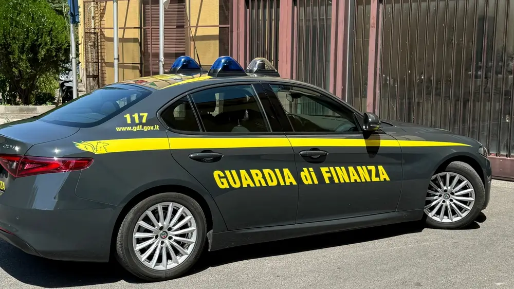 Veicolo della Guardia di Finanza in servizio di pattuglia urbana con livrea grigia e gialla e lampeggianti blu.