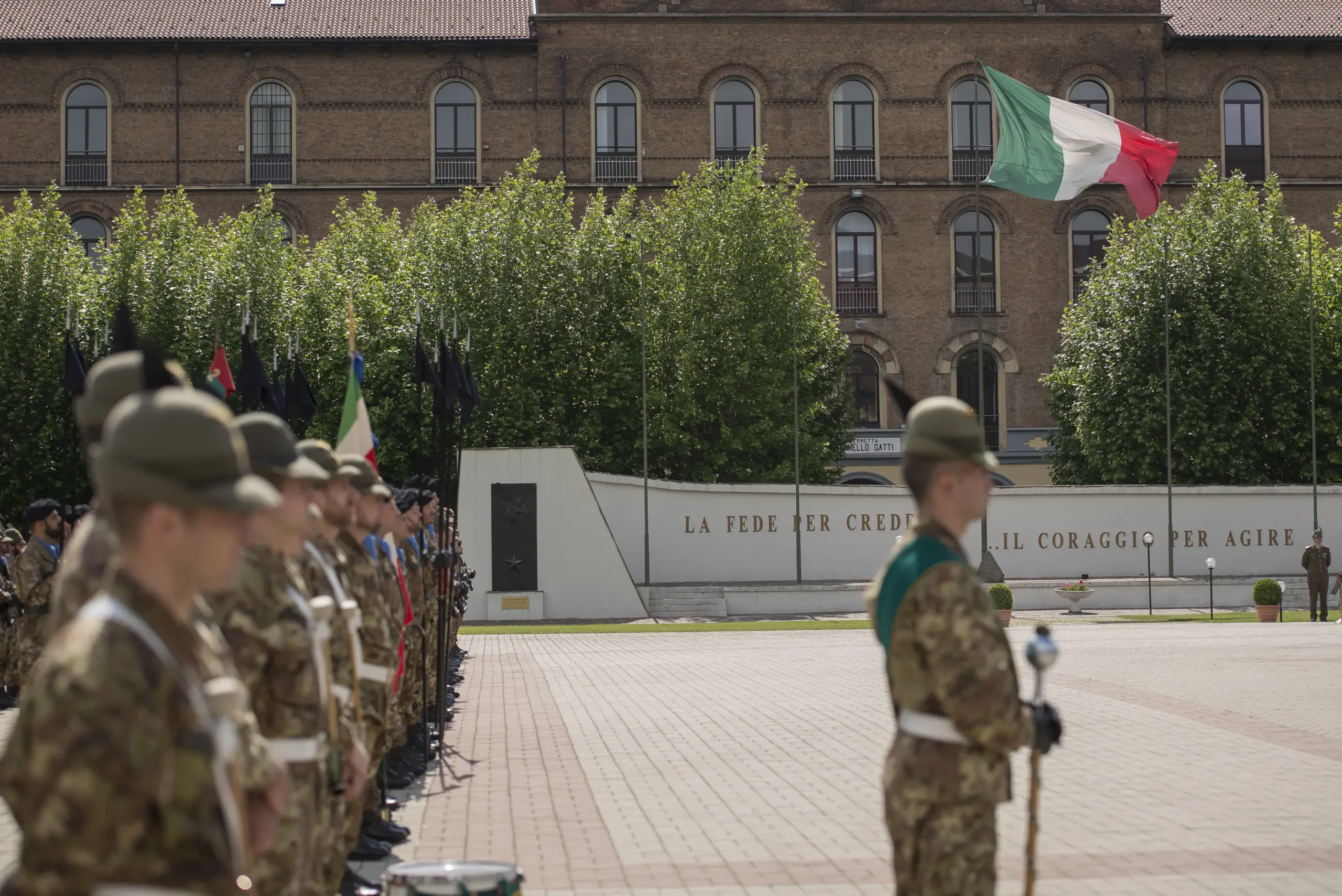 Militari in divisa schierati nel piazzale di un centro reclutamento sede di concorso con la bandiera italiana.